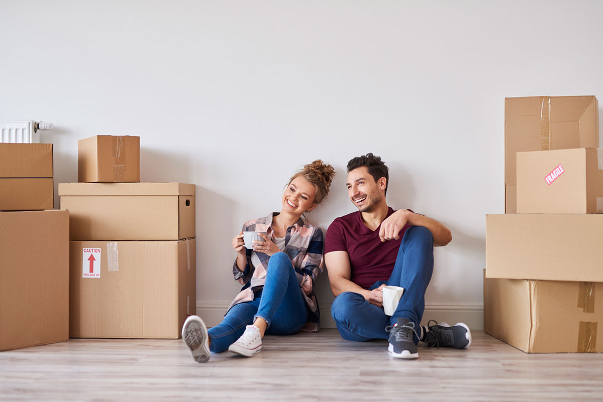 Couple sitting on the floor in new home surrounded by moving boxes